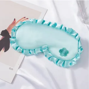 Nahaufnahme des eleganten Satin Schlafmaske Details mit süßer gestickter Blumenverzierung.