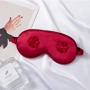Silk sleep mask detail view featuring elegant red fabric and embroidered floral patterns.