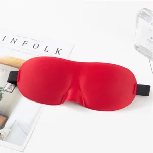 Máscara de dormir 3D roja contorneada en primer plano, sombreado suave para viaje.