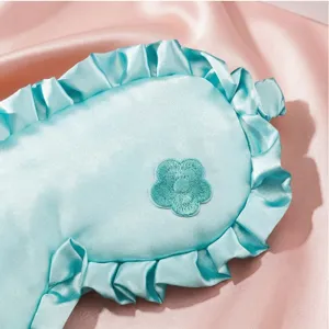 Hellblaue Satin-Schlafmaske mit Rüschen und niedlicher bestickter Blume für guten Schlaf.