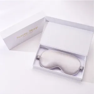 Detail view of a smooth silk eye mask in an elegant white gift box for relaxing sleep.