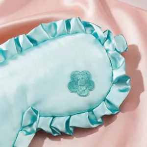 Weiche hellblaue Satin Schlafmaske mit Rüschenrand und hübscher Blumenstickerei für Reisen.