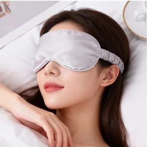 Gros plan détaillé d'un masque de sommeil en soie argentée lisse, texture douce et confortable.