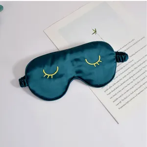 Dunkelgrüne Seiden-Schlafmaske Detail mit feinen gelben Wimpernstickereien und Gummiband.