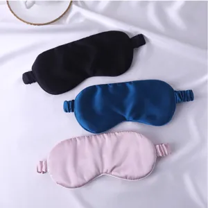 Gros plan détaillé de masques de sommeil en soie de mûre lisse en noir, bleu et rose.