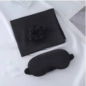 Black silk satin sleep mask hair scrunchie and pillowcase three piece set for nighttime rest.