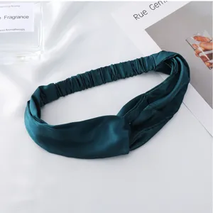 Detail view of a dark green imitation silk cross headband with comfortable elastic band.