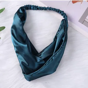 Nahaufnahme des dunkelgrünen Satin-Kopfbands mit verdrehtem Design und edlem Seidenglanz.