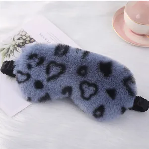 Dettaglio mascherina in peluche blu con morbida pelliccia e motivo leopardato a cuori.