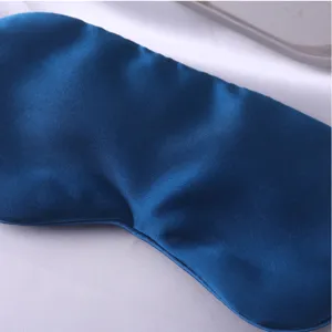 Gros plan du masque de sommeil en soie bleu foncé lisse montrant une texture de tissu délicate.