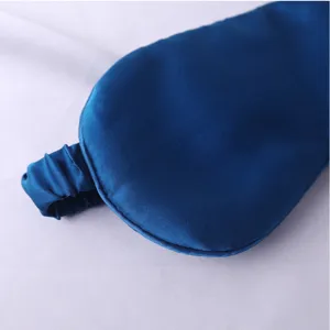 Détail en gros plan d'un masque de sommeil en soie bleu foncé avec sangle élastique douce.