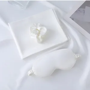 White silk sleep set including eye mask, scrunchie and pillowcase for comfortable rest.