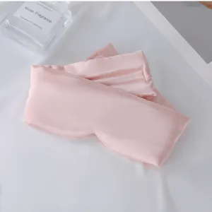 Detalle antifaz de seda rosa, tejido satinado liso, sombreado comodo para dormir viaje.