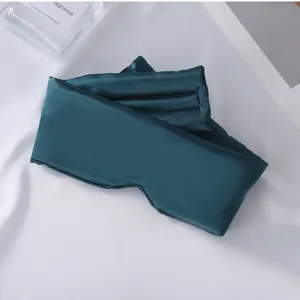 Detalle de máscara de dormir de seda sintética verde oscura con textura suave y diseño.