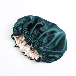 Detailansicht der dunkelgrünen Seidensatin-Schlafkappe mit rosa Futter und Gummizug.
