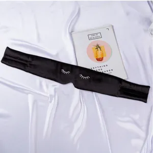 Primer plano detallado del antifaz de seda negra para dormir con bordado de pestañas y velcro.