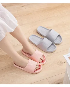 Close-up of cozy thick-sole home slippers on wooden floor, soft and anti-slip design.