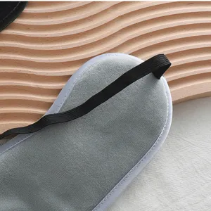 Primer plano del detalle del suave antifaz de dormir gris, textura afelpada con correa elástica.