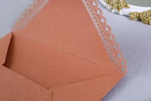 Close-up detail of a brown paper envelope featuring elegant laser-cut lace heart patterns.