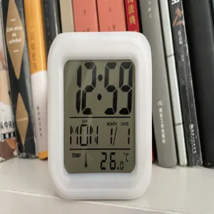 White digital alarm clock with LCD screen showing time, date, day and temperature clearly.