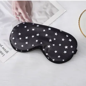 Detailed view of black silk sleep mask with white star print, soft texture for travel nap.