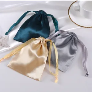 Detailansicht mehrerer Satinsäckchen mit Kordelzug in Grün Gold und Grau für Schmuck Aufbewahrung.