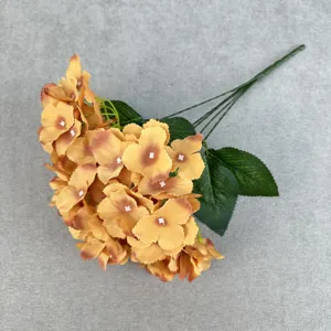 Close-up detail of artificial yellow hydrangea flowers with multi-fork silk petals and green leaves.