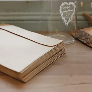 Close up of vintage brown kraft paper envelopes stack on wooden desk, simple detail shot.