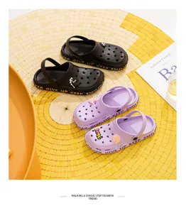 Detailed shot of cute cartoon hole shoes in black and purple colors placed on a yellow mat.
