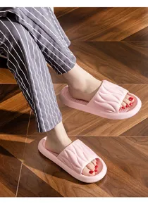 Detailed shot of comfortable pink open-toe home slippers with soft thick sole and wavy design.
