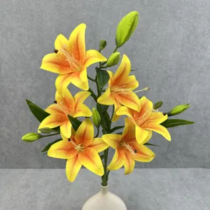 Artificial lily flower detail shot, yellow and orange gradient blooms with green leaves.