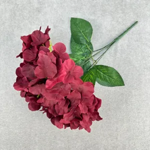 Artificial hydrangea flower branch fake silk floral dark red home decor detail shot.