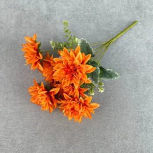Detailansicht des leuchtend orangefarbenen künstlichen Dahlienblumenstraußes mit grünen Blättern.