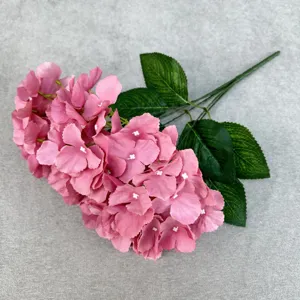 Close-up detail of artificial hydrangea flower petals and green leaves, delicate silk texture.