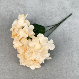 Close-up detail of champagne artificial hydrangea flower branch with realistic green leaves.