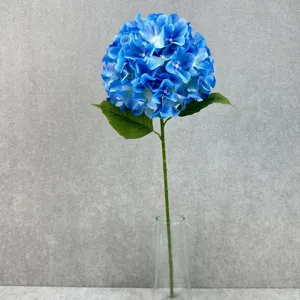 Artificial blue hydrangea single stem with leaves in glass vase for home wedding decor setup.