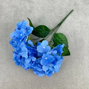 Detailed view of blue artificial hydrangea flower branches with realistic green leaves for decor.