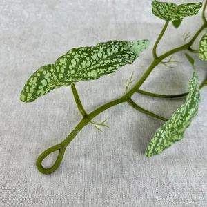 Close-up detail of artificial green vine with speckled leaves, perfect for wall decoration.