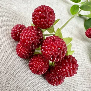 Close-up detail of artificial red berry branch with green leaves for home decoration.