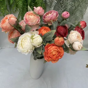 Detailansicht eines bunten künstlichen Pfingstrosen-Blumenarrangements in einer weißen Vase.