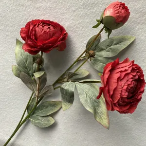 Detailansicht eines künstlichen roten Pfingstrosen-Blumenzweigs mit grünen Blättern