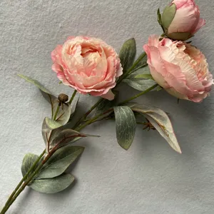 Nahaufnahme eines künstlichen rosa Pfingstrosenblütenzweigs mit realistischen grünen Blättern.