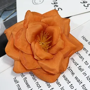 Primer plano detallado de rosa artificial de tela naranja, ideal para decoración.
