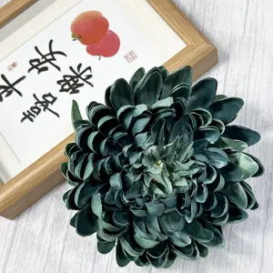 Detailed close-up view of artificial dark green chrysanthemum flower head with realistic fabric texture.