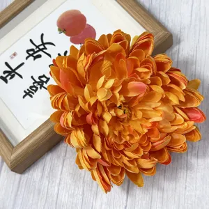 Artificial orange chrysanthemum flower head for hotel mall window decoration and floral arrangement.