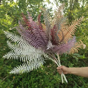 Artificial fern leaves, colorful decorative plant branches for home wedding floral decor.