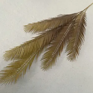 Artificial cycad leaf detail shot, gold palm plant branch for Nordic home decor and floral arrangement.