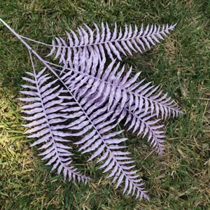 Detailed close-up view of artificial purple Boston fern leaves for plant wall decor.