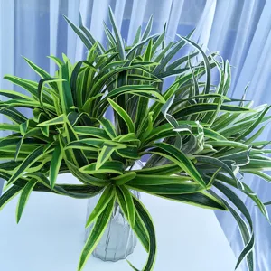 Vue détaillée de feuilles de plantes artificielles vertes à bord blanc dans un vase en verre transparent.