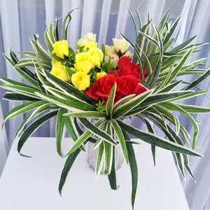 Plante en pot artificielle avec roses jaunes et rouges et feuilles vertes à bord blanc pour intérieur.